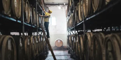 Man on ladder checking barrels.